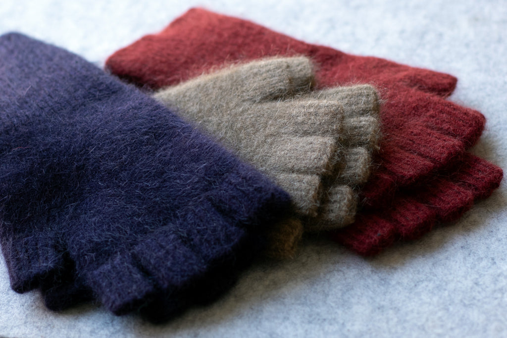 Group of coloured fingerless gloves in a merino wool, possum and silk blend. Colours are Aubergine, camel and red