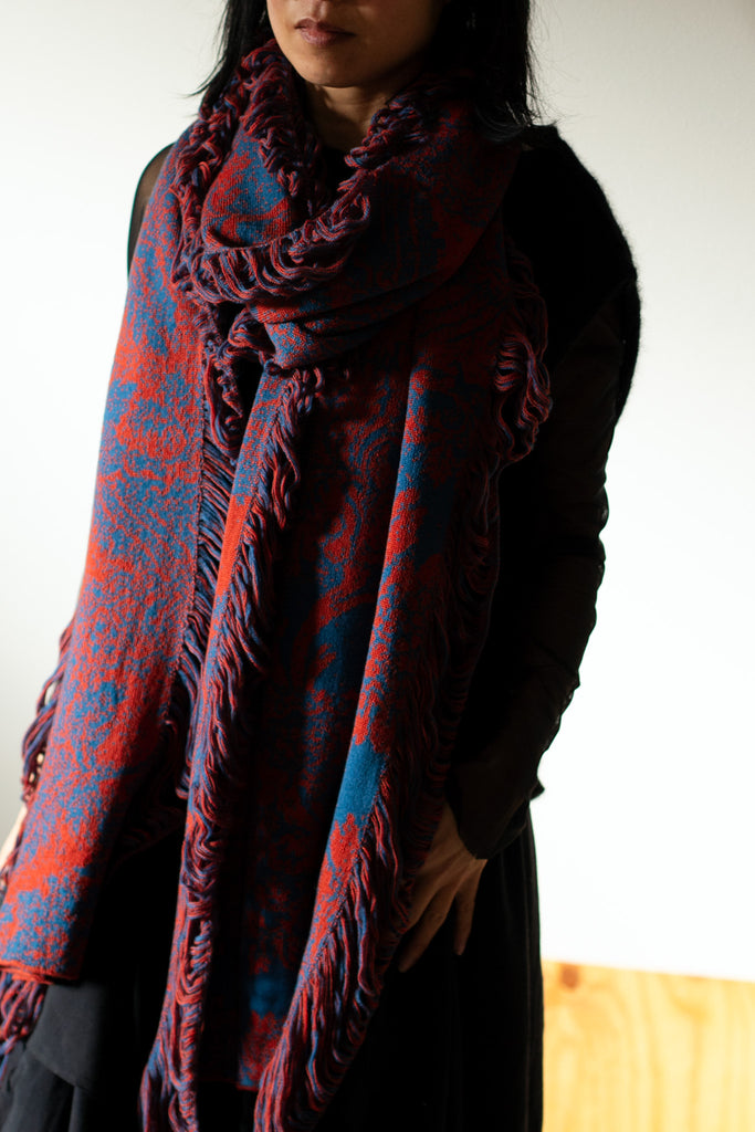 Model wears wool damask patterned scarf in a rust and lagoon colourway. Designed by Wendy Voon and made in Melbourne.
