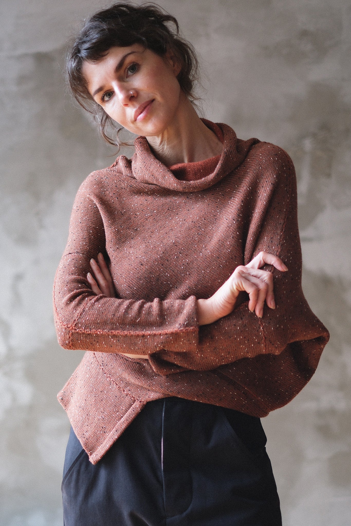 Model wears wool bias knit jumper in terracotta flecked colourway.