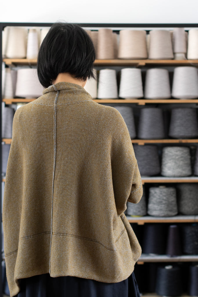 Back view of model wearing a wool boxed shaped jumper in mustard backed with grey merino wool,  designed and made in Melbourne by Wendy Voon knits.