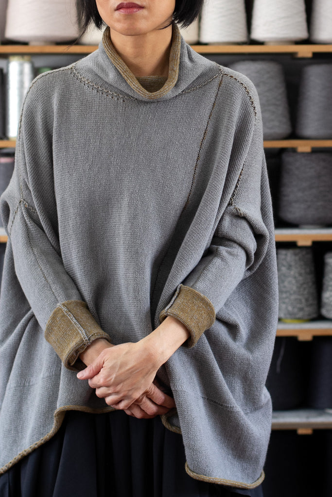 Front view of model wearing a wool boxed shaped jumper in mustard backed with grey merino wool, worn inside out, worn inside out, designed and made in Melbourne by Wendy Voon knits.