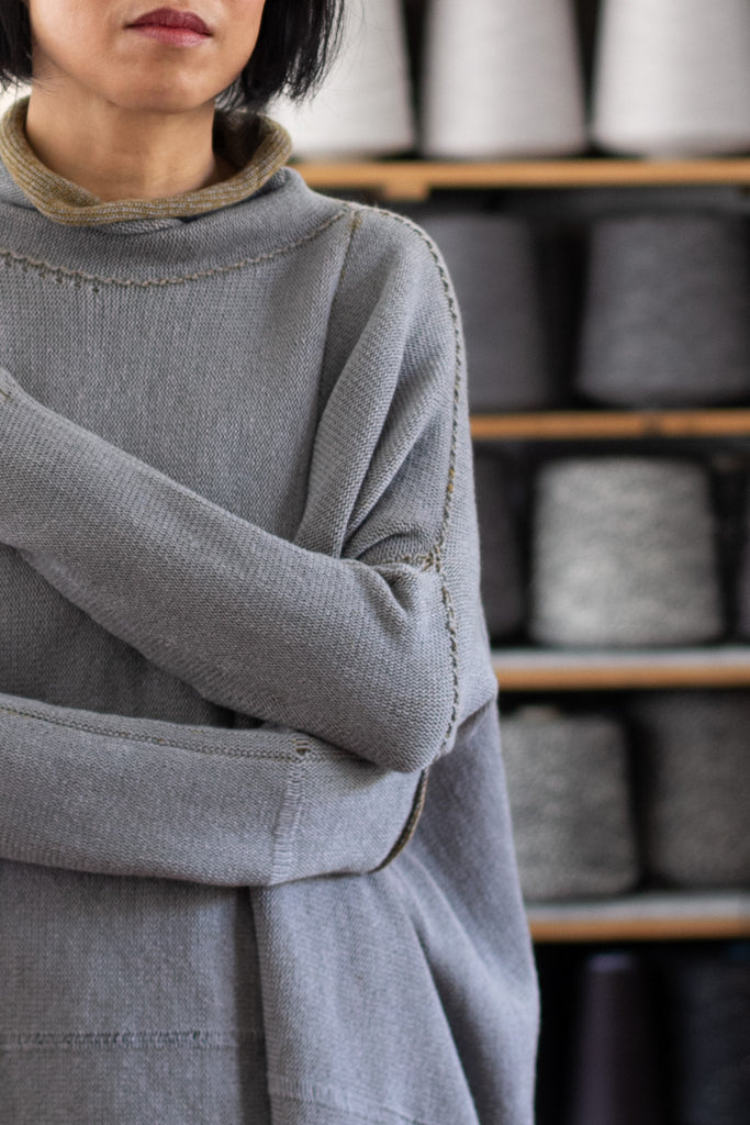 Front view of model wearing a wool boxed shaped jumper in mustard backed with grey merino wool, worn inside out, designed and made in Melbourne by Wendy Voon knits.