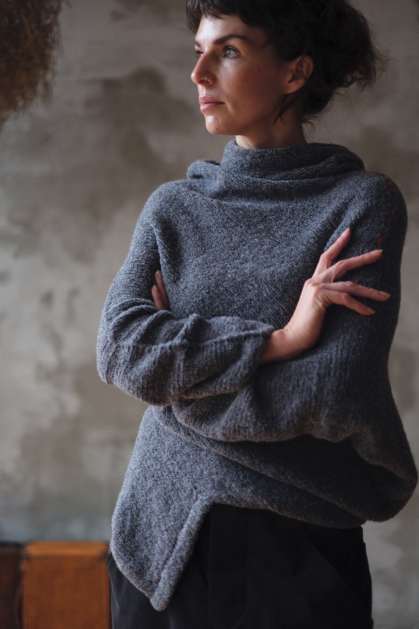 Woman wearing a textured gray sweater with orange shoulder seam detail against a neutral background