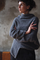 Woman wearing a textured gray sweater with orange shoulder seam detail against a neutral background
