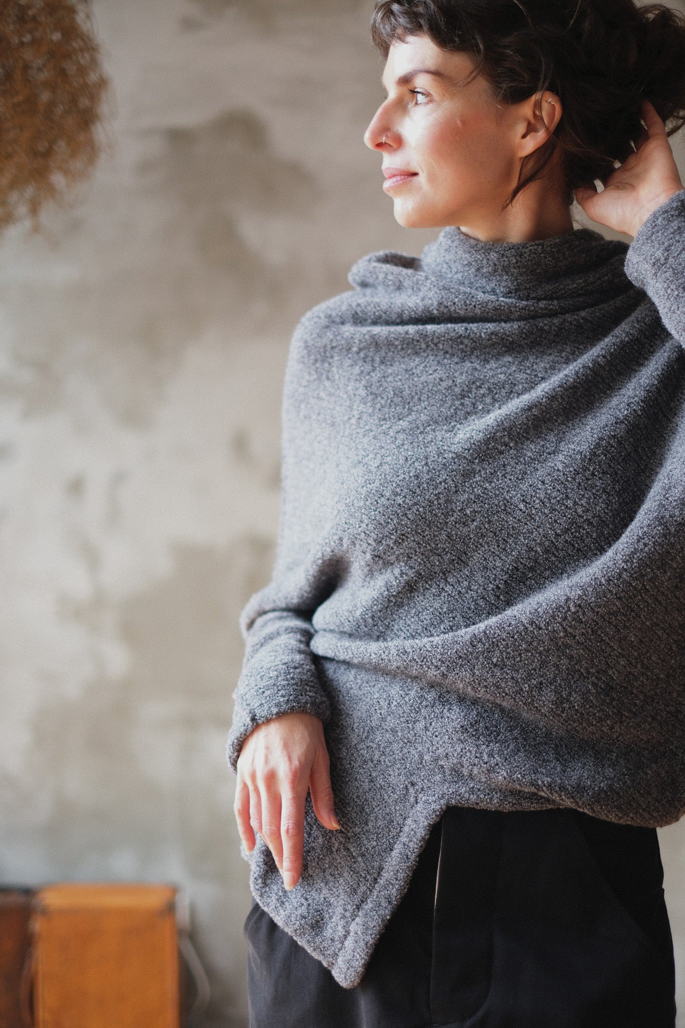 Woman wearing a textured gray sweater with orange shoulder seam detail against a neutral background