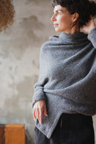 Woman wearing a textured gray sweater with orange shoulder seam detail against a neutral background