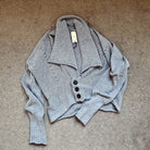 Soft grey knitted cardigan with buttons on a beige carpet