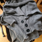 Soft grey knitted cardigan with black buttons on a chair