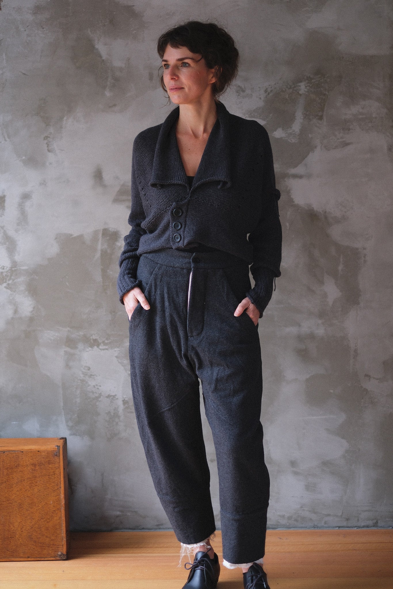 A woman wearing a charcoal gray chunky knit cardigan with 3 buttons.