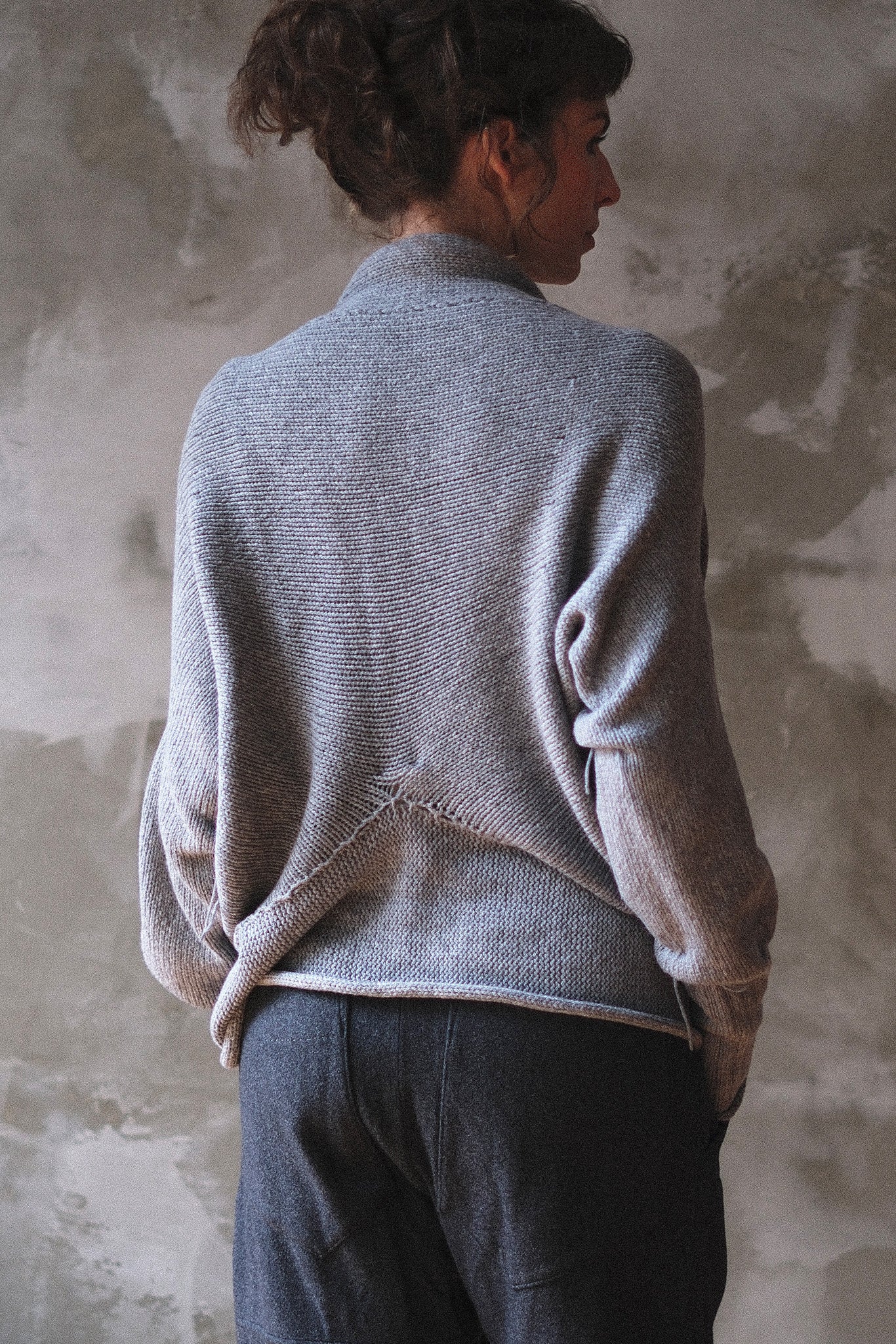 Back view of model wearing soft grey chunky knut cardi upside down.