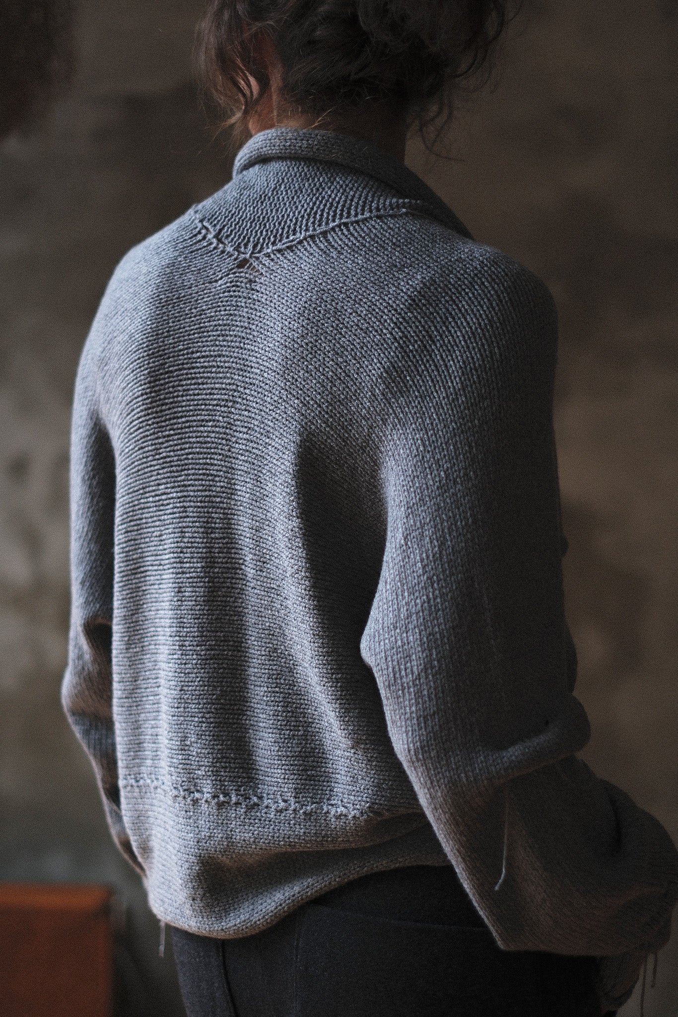 Back view of model wearing a soft grey chunky knit cropped cardigan.