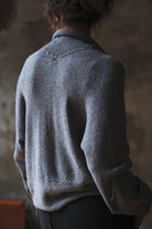 Back view of model wearing a soft grey chunky knit cropped cardigan.