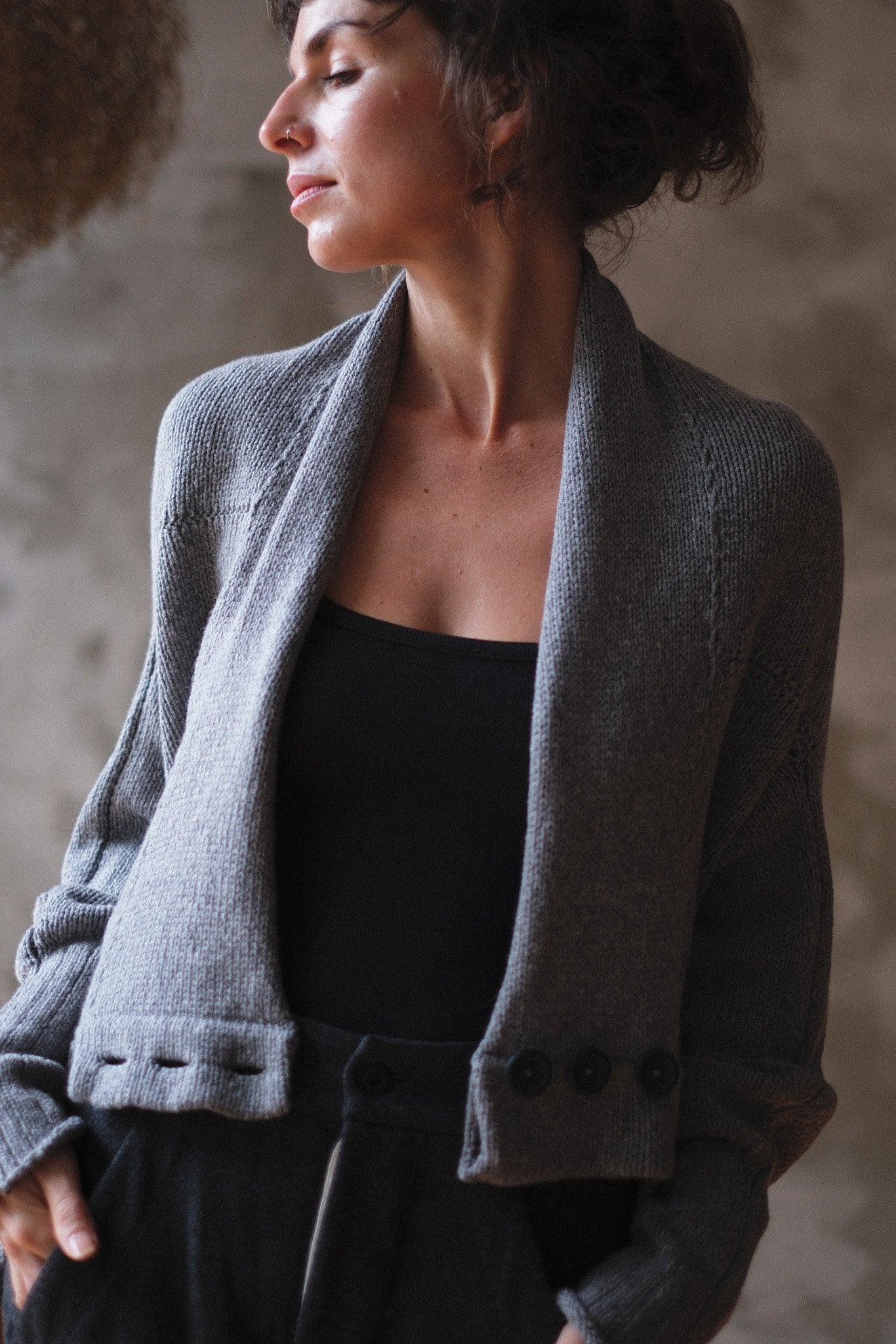 Model wears soft grey chunky knit cardi upside down.