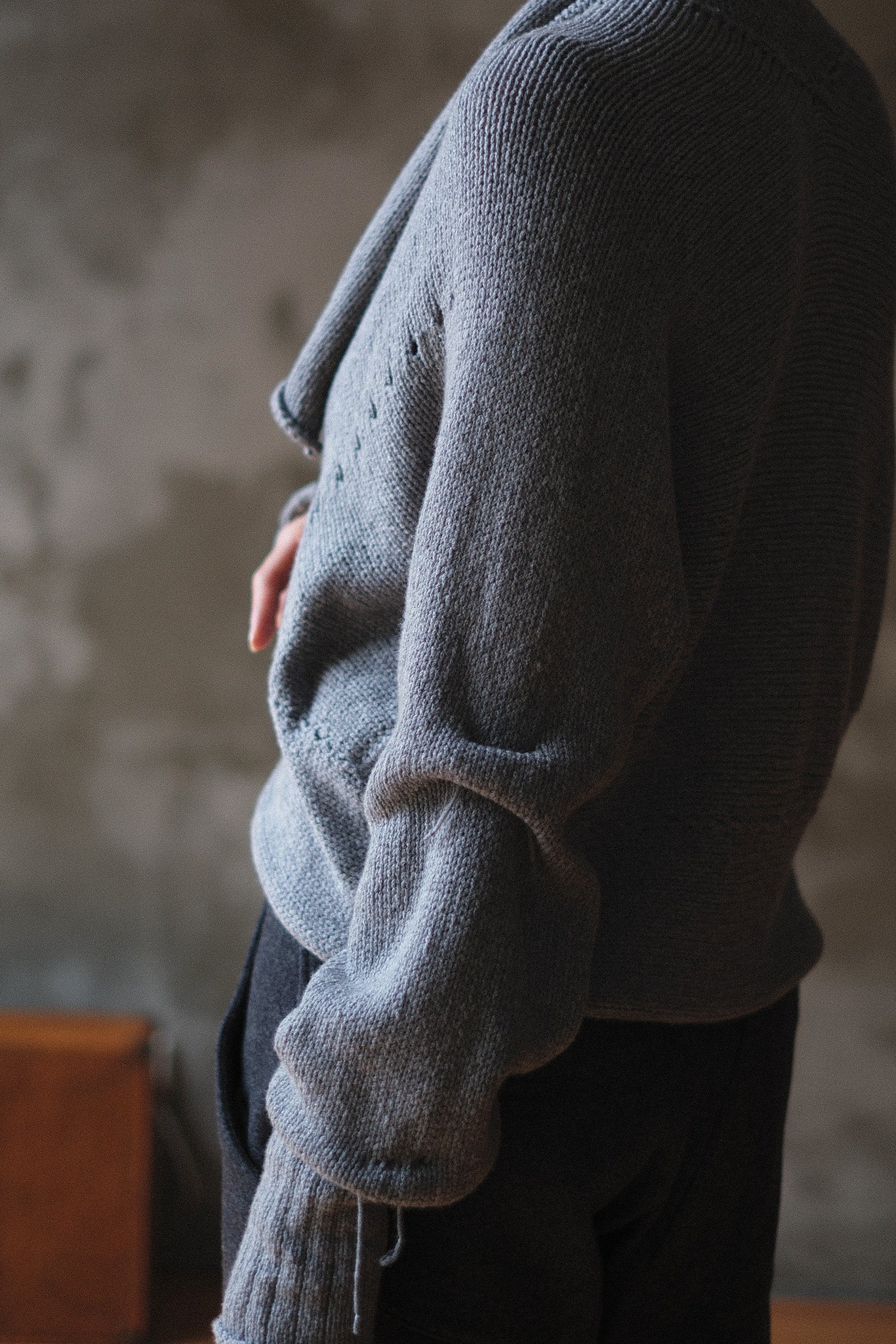 Models wears a soft grey chunky knit cropped cardigan with a shawl collar and ruched sleeve detail.
