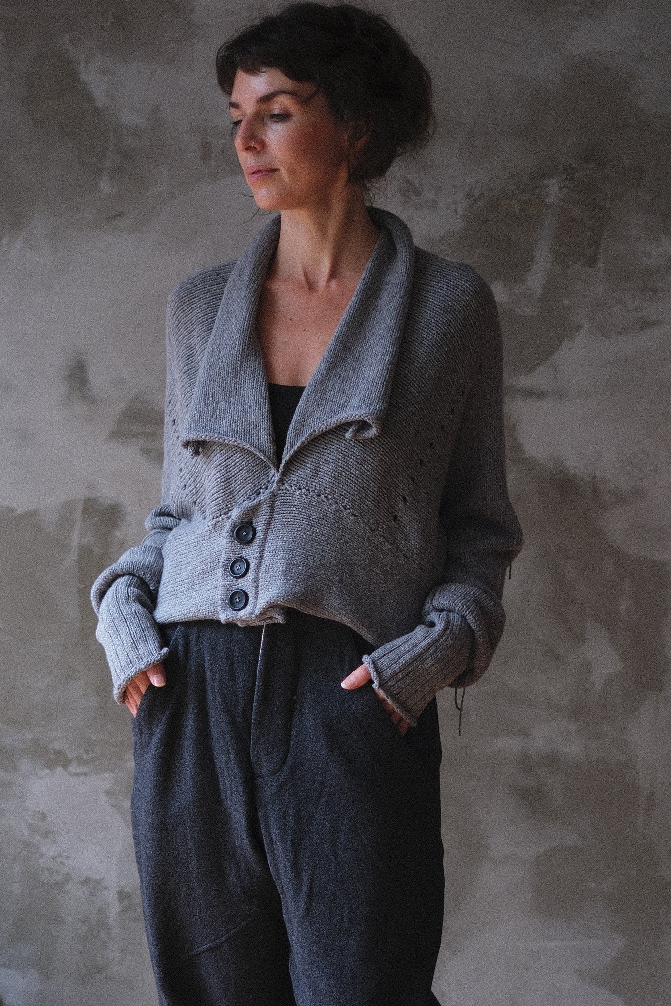 Models wears a soft grey chunky knit cropped cardigan with a shawl collar and  3 button front/