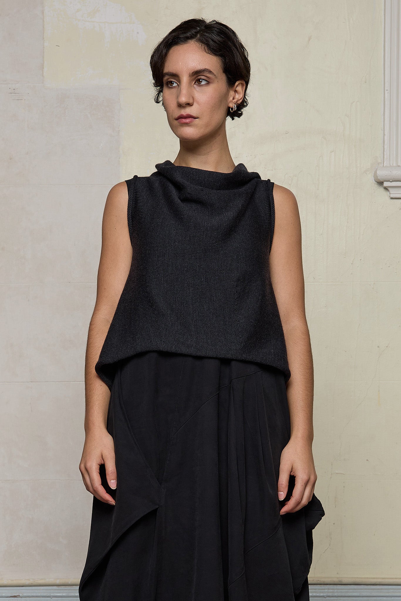 Model wears knitted charcoal asymmetric self curling vest, back to front. Designed and knitted in Melbourne by Wendy Voon knits