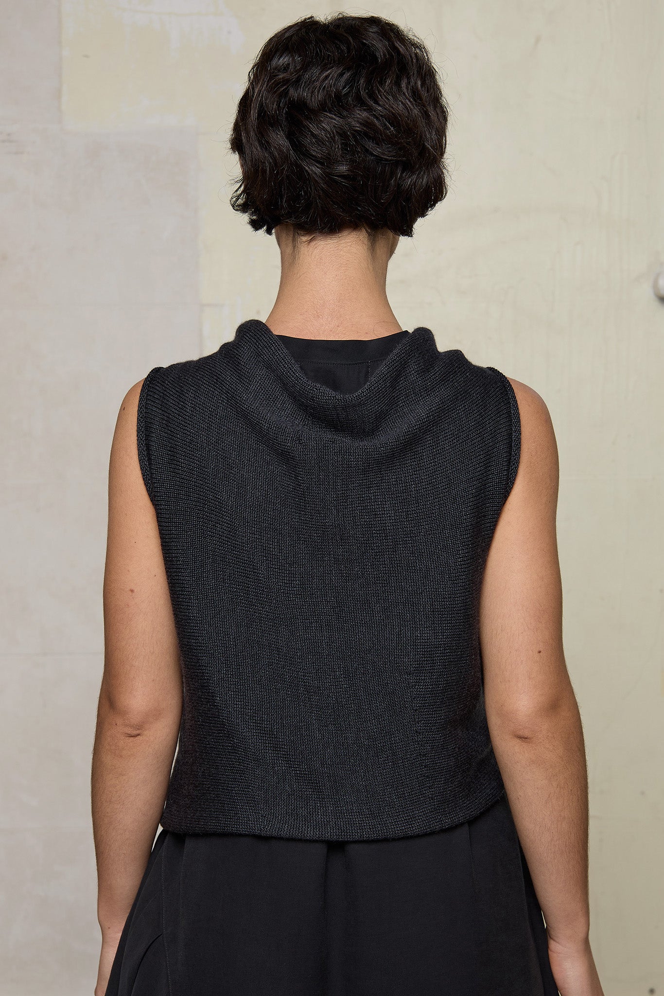 Model wears knitted charcoal asymmetric self curling vest. Designed and knitted in Melbourne by Wendy Voon knits