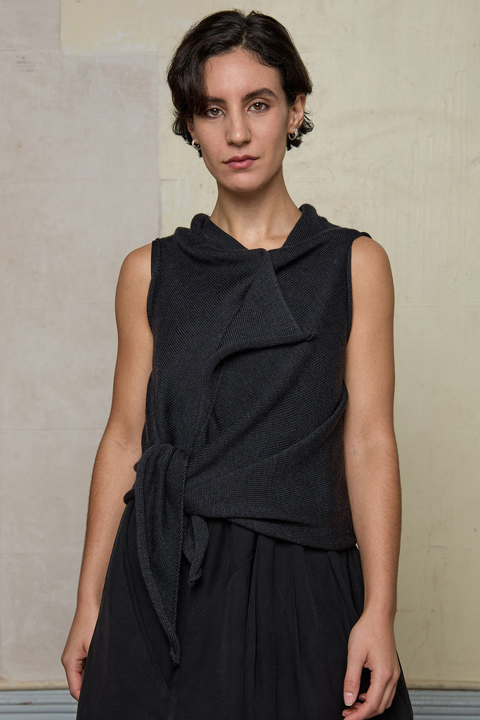 Model wears knitted charcoal asymmetric self curling vest, cinched at waist. Designed and knitted in Melbourne by Wendy Voon knits