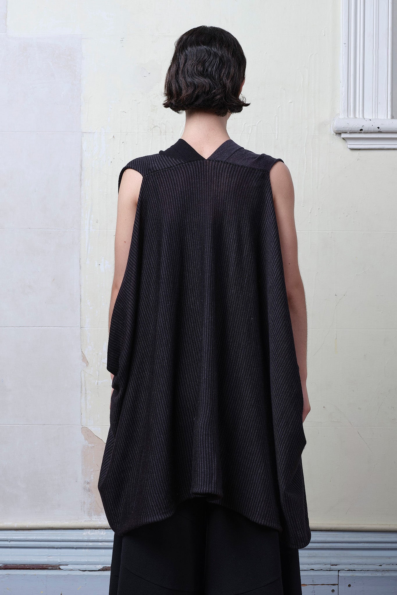 Back view of model wearing a superfine merino wool striped wrap, in charcoal/black colourway. Designed and made in Melbourne by Wendy Voon knits.