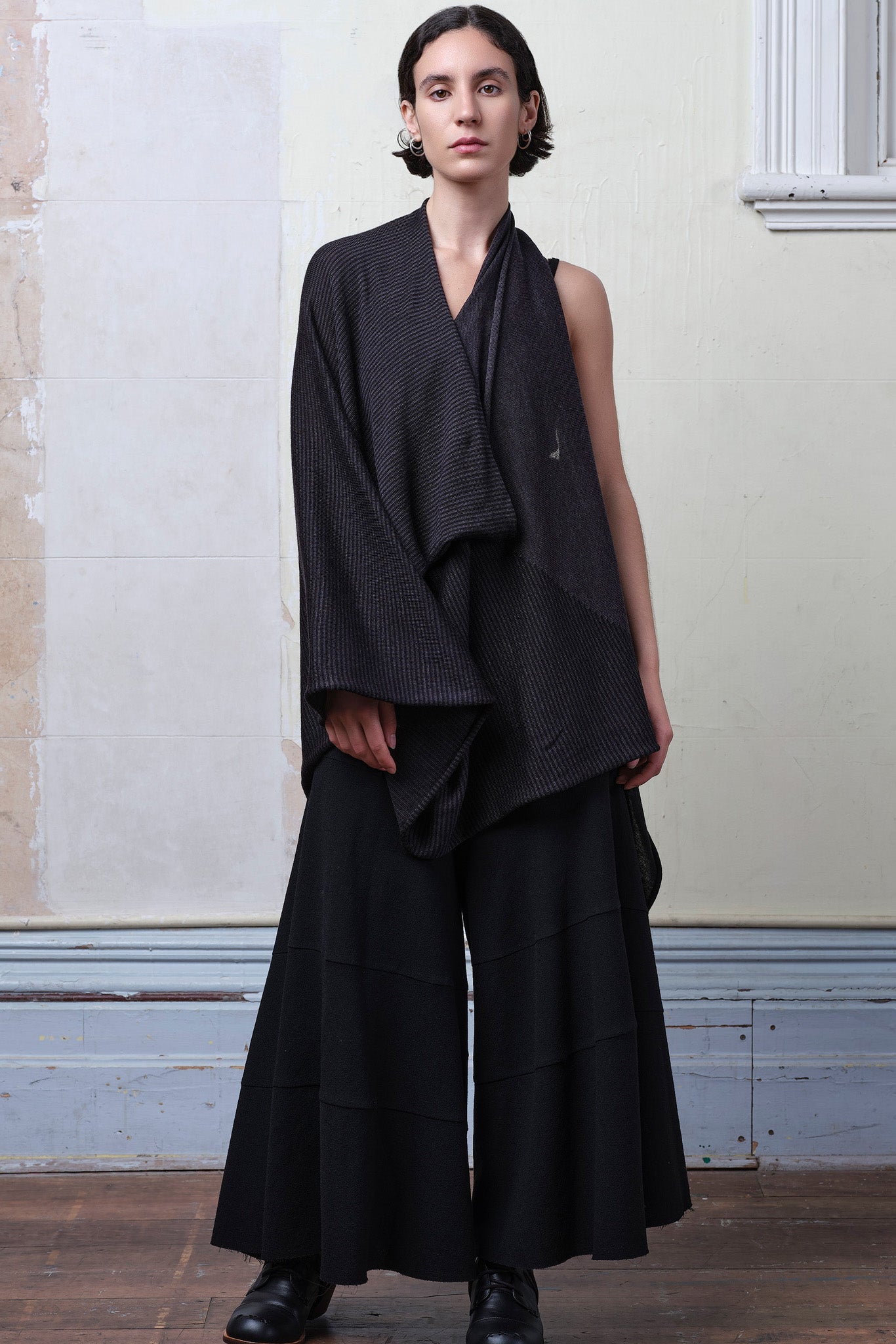 Model wears a wool striped wrap, with arm through neckline, and head through an armhole, in charcoal/black colourway. Designed and made in Melbourne by Wendy Voon knits.