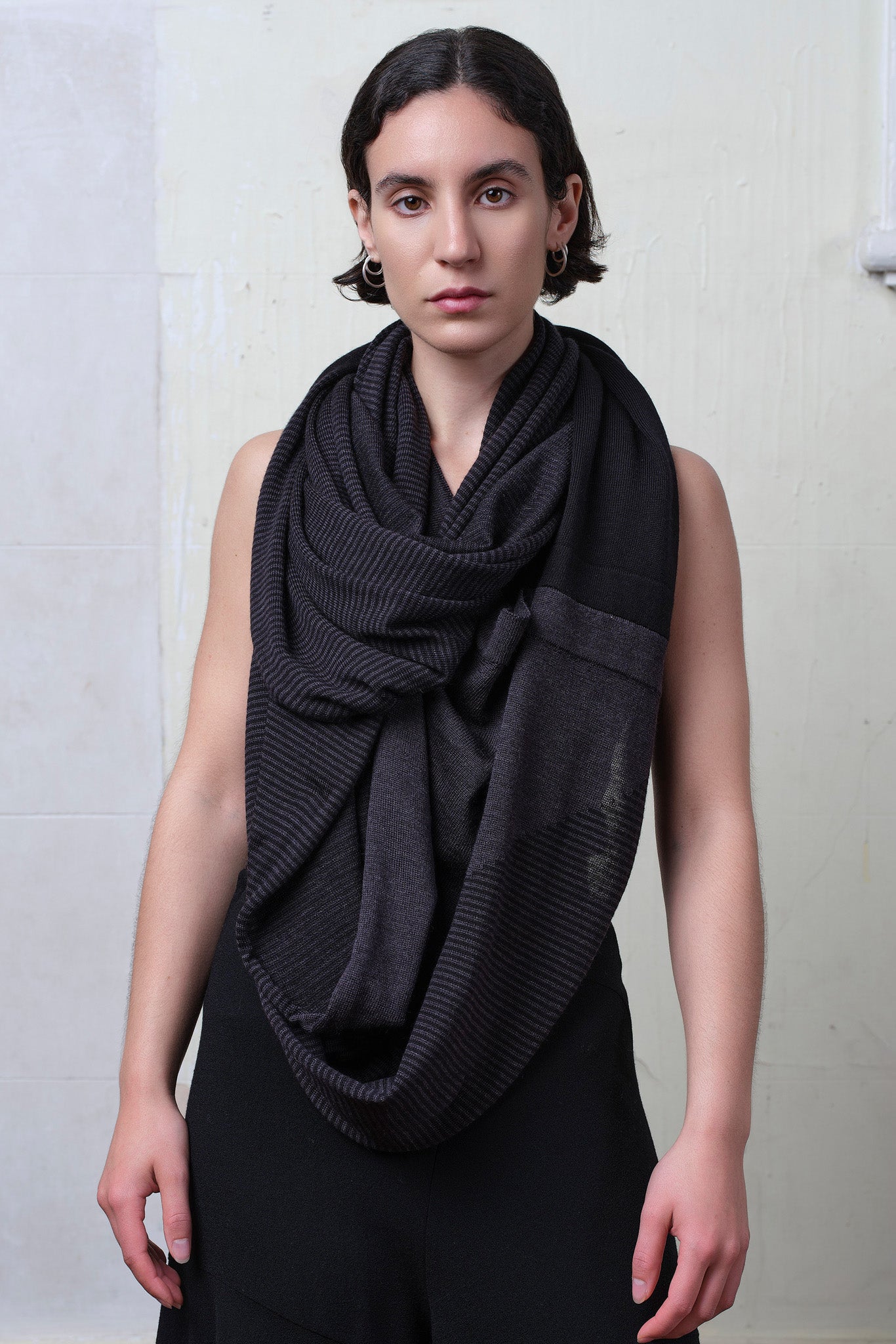 Model wears a wool striped wrap as a scarf , in charcoal/black colourway. Designed and made in Melbourne by Wendy Voon knits.