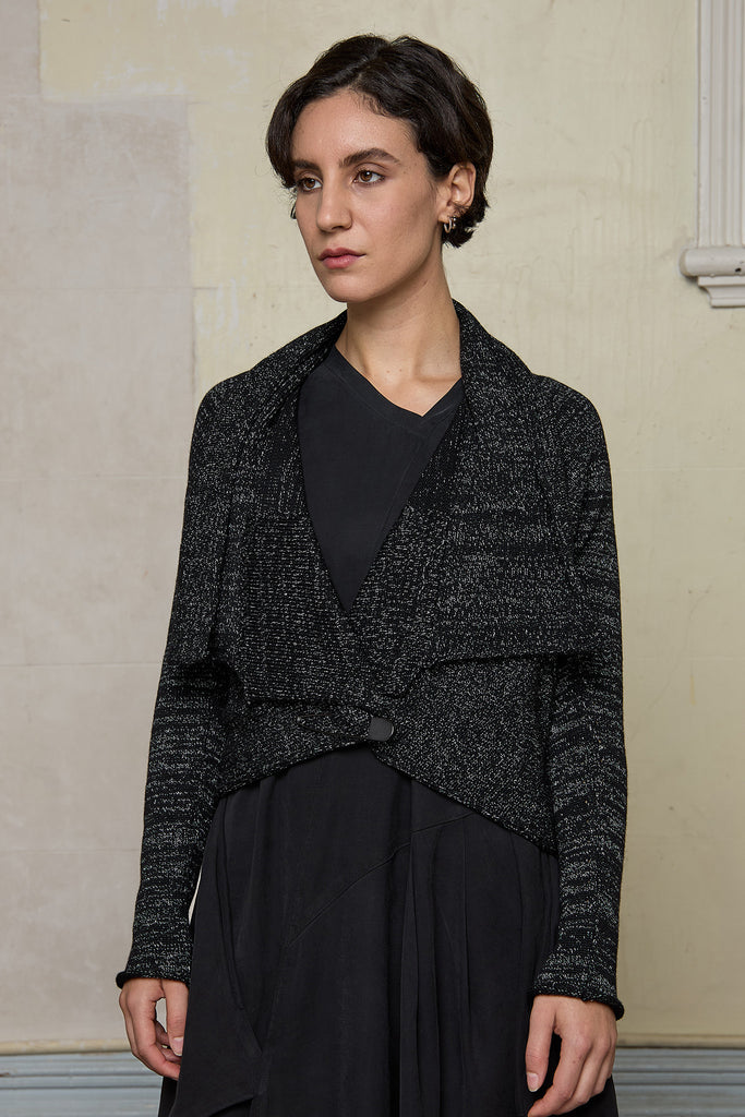 Model wears a black with white flecks shawl collared cardigan upside down, and is cinched at the waist with a safety pin.