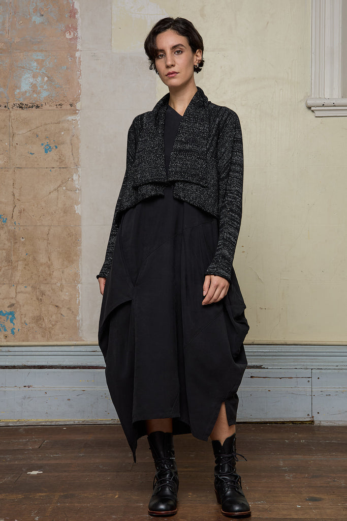 Model wears a black with white flecks shawl collared cardigan upside down.