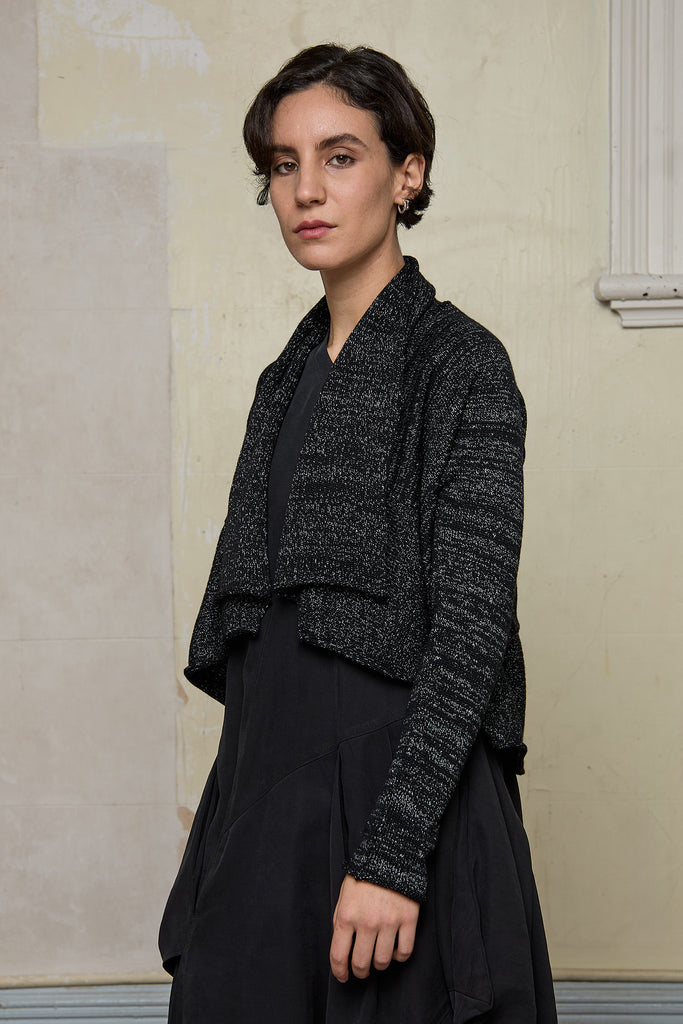 Model wears a black with white flecks shawl collared cardigan upside down.