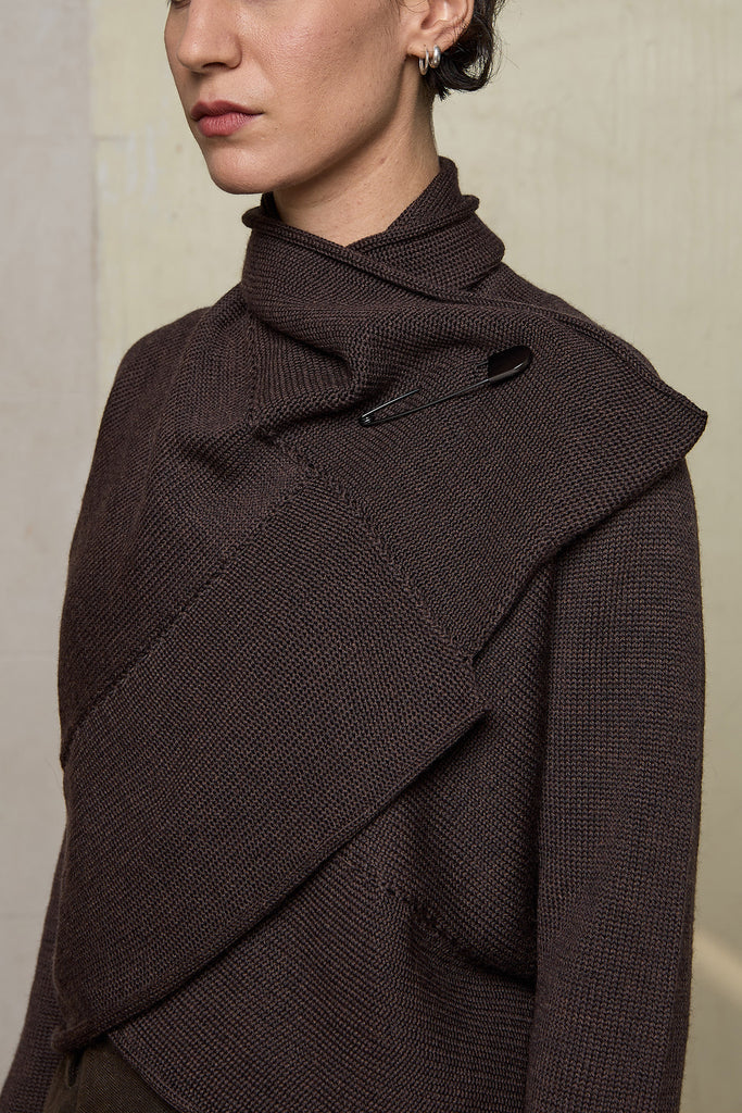 Model wears a knitted shawl collared cardigan upside down and pinned at the neck in a chocolate brown colourway.  Cardigan is designed and knitted in  Melbourne by Wendy Voon knits.