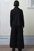 Model wears knitted merino cross over, slung behind, in black colourway.