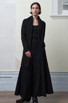 Model wears knitted merino cross over, slung behind, in black colourway.