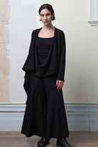 Model wears knitted merino cross over, undone, in black colourway.