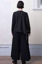 Model wears knitted merino cross over, undone, in black and charcoal colourway.
