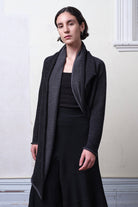 Model wears knitted merino cross over, slung behind, in black and charcoal colourway.