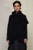 Model wears black knitted coat upside down, made from alpaca and superfine merino wool.
