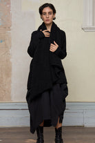 Model wears black knitted coat upside down, made from alpaca and superfine merino wool.