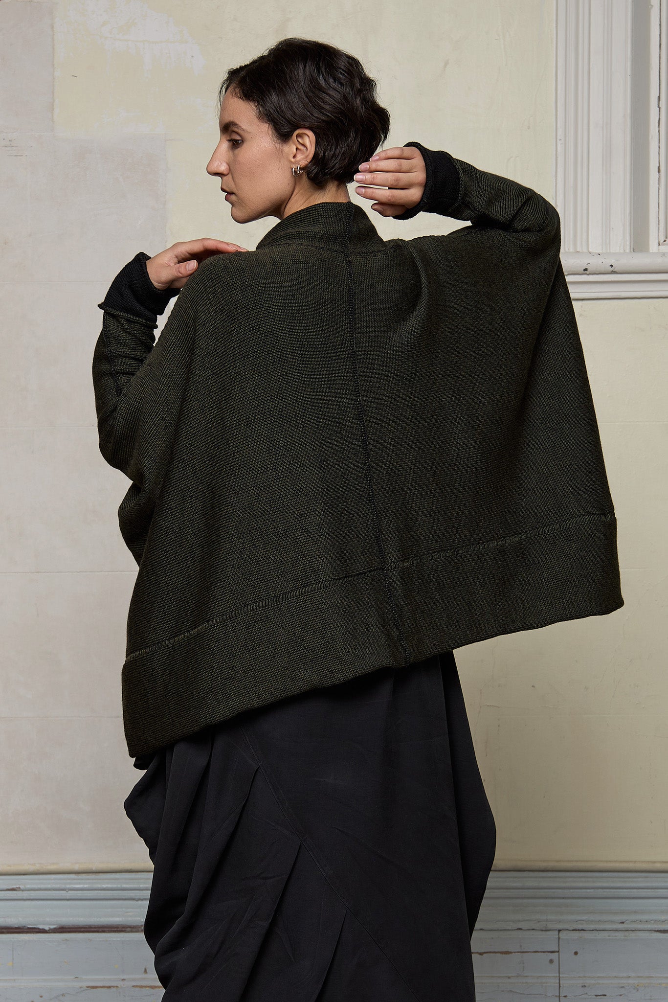 Back view of box shaped jumper designed by Wendy Voon, in an army with black backed fabric, made from superfine merino wool.