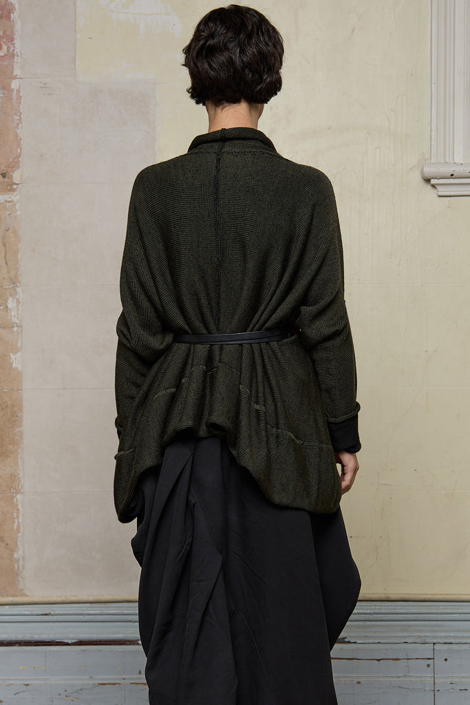 Back view of box shaped jumper, worn belted.  Designed by Wendy Voon, in an army with black backed fabric, made from superfine merino wool.
