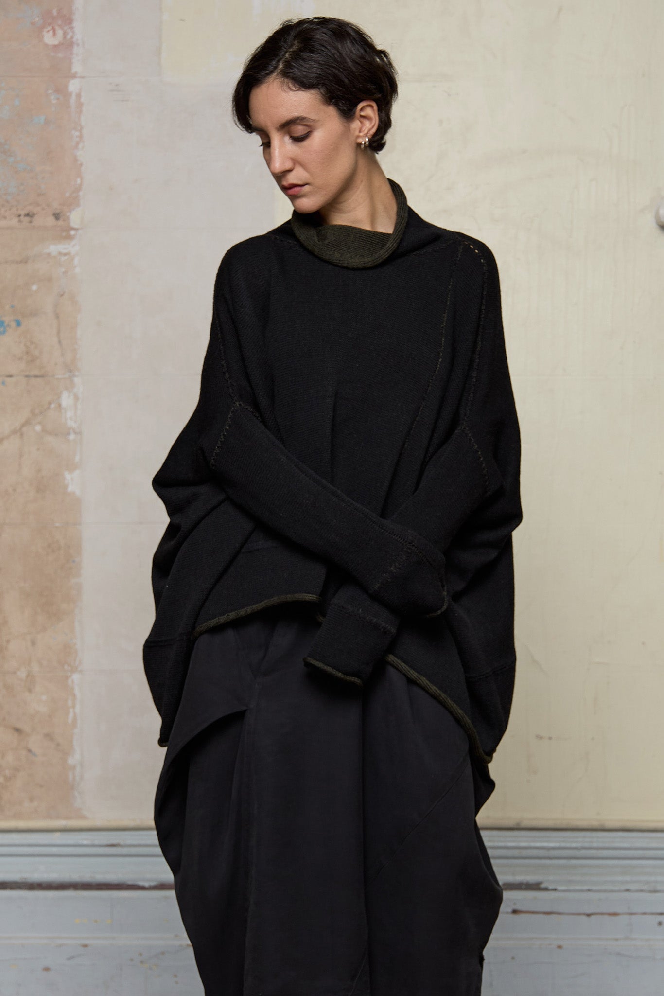 Front view of box shaped jumper designed by Wendy Voon, in an army with black backed fabric, worn inside out.  Made from superfine merino wool.