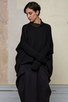 Front view of box shaped jumper designed by Wendy Voon, in an army with black backed fabric, worn inside out.  Made from superfine merino wool.