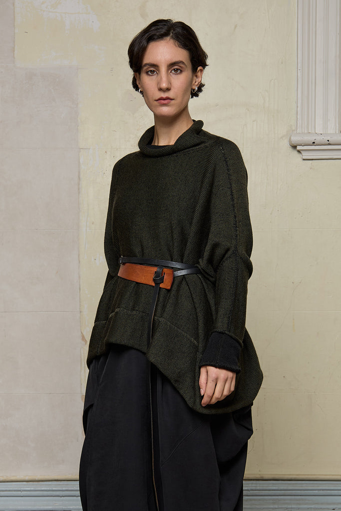 Front view of box shaped jumper designed by Wendy Voon, in an army with black backed fabric, worn belted. Made from superfine merino wool.