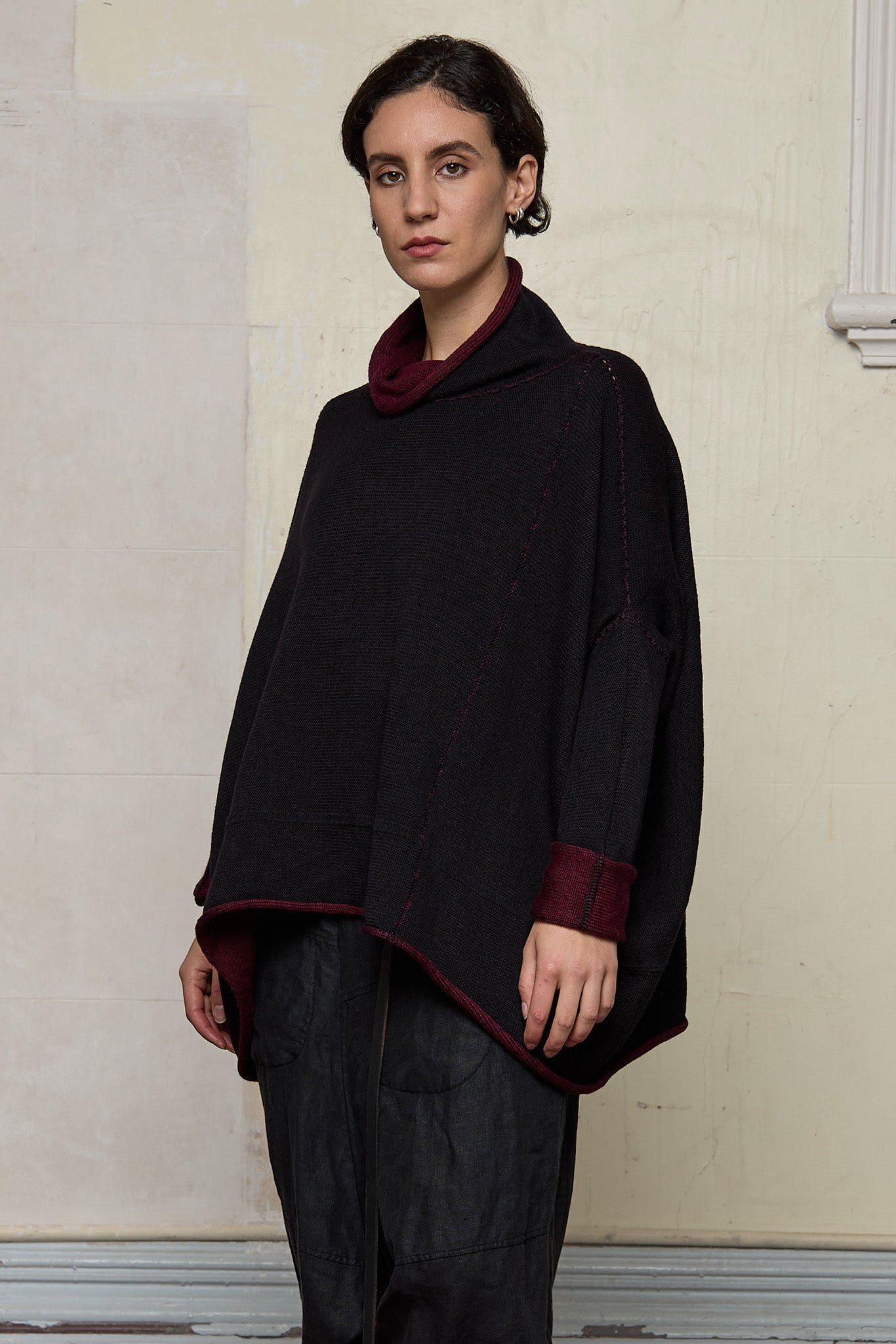 Front view of box shaped jumper designed by Wendy Voon, in a burgundy with black backed fabric, worn inside out.  Made from superfine merino wool.