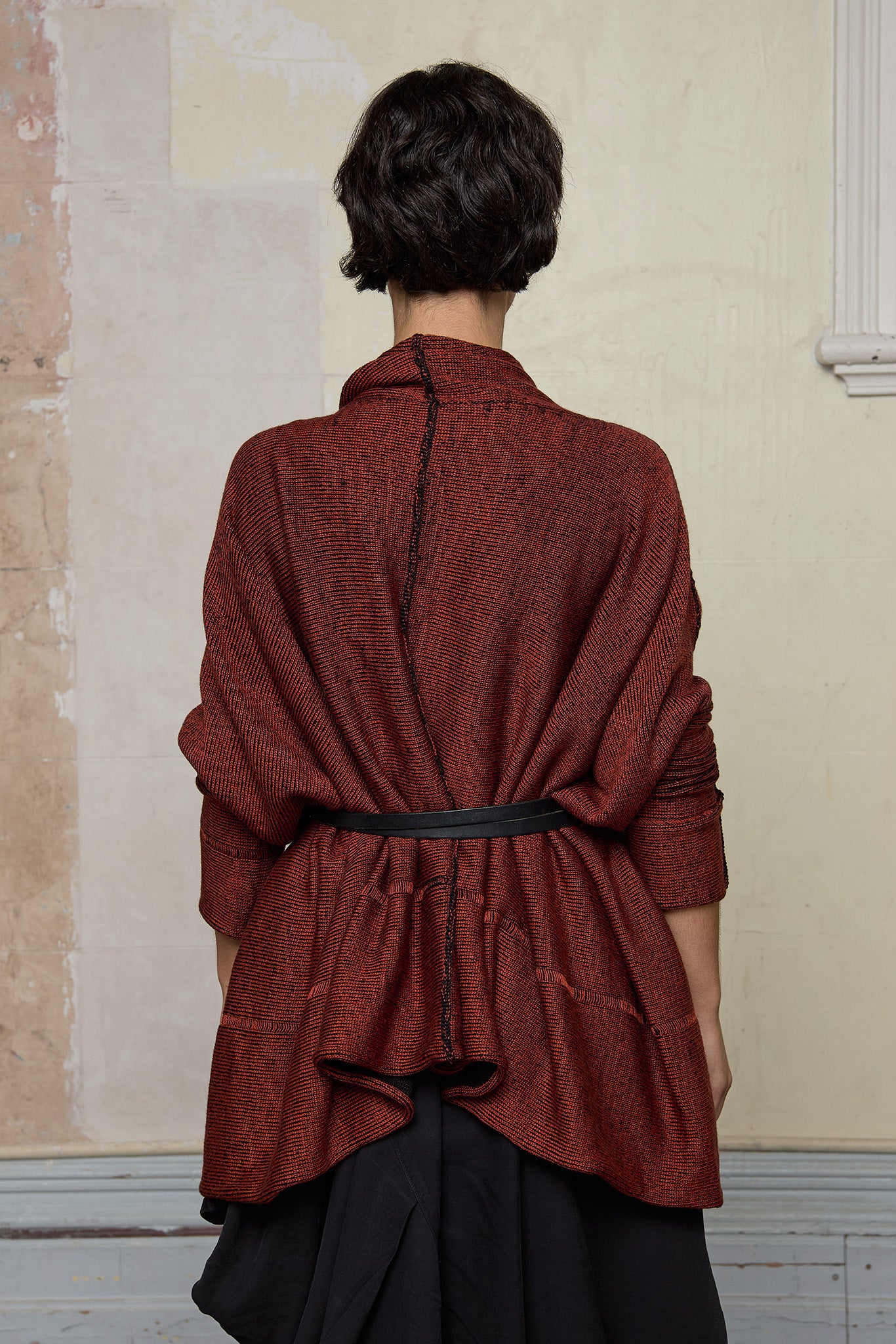 Back view of box shaped jumper designed by Wendy Voon, in a vermillion with black backed fabric, worn belted. Made from superfine merino wool.