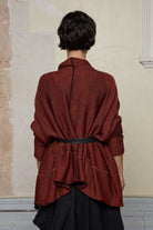 Back view of box shaped jumper designed by Wendy Voon, in a vermillion with black backed fabric, worn belted. Made from superfine merino wool.