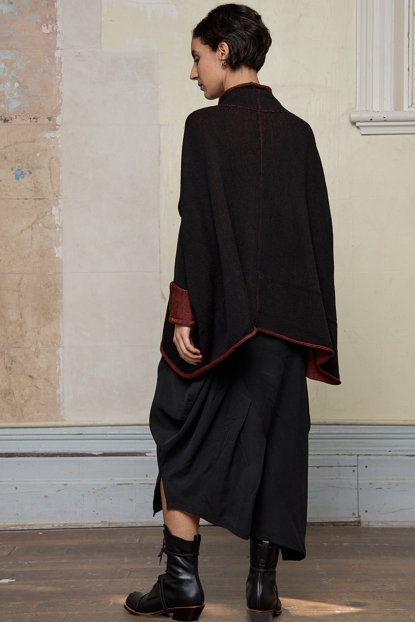 Back view of box shaped jumper designed by Wendy Voon, in a vermillion with black backed fabric, worn inside out. Made from superfine merino wool.