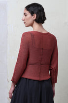 Back 3/4 view of model wearing Cotton Batwing  in coral colourway, featuring large stitch details,  designed by Wendy Voon knits.