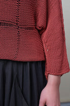 Close up fabric detail of Cotton Batwing  in coral colourway, featuring large stitch details,  designed by Wendy Voon knits.