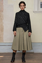 Full body front view of Bias jumper, a design by Wendy Voon knits in a black flecked with white merino wool and linen/cotton blend fabric. 