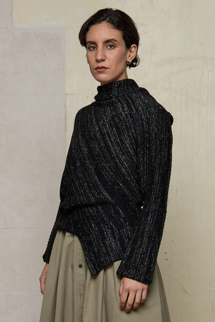 Side view of Bias jumper, a design by Wendy Voon knits in a black flecked with white merino wool and linen/cotton blend fabric. 