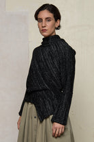 Side view of Bias jumper, a design by Wendy Voon knits in a black flecked with white merino wool and linen/cotton blend fabric. 